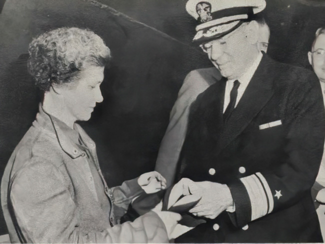 woman receiving a merit flag from an admiral