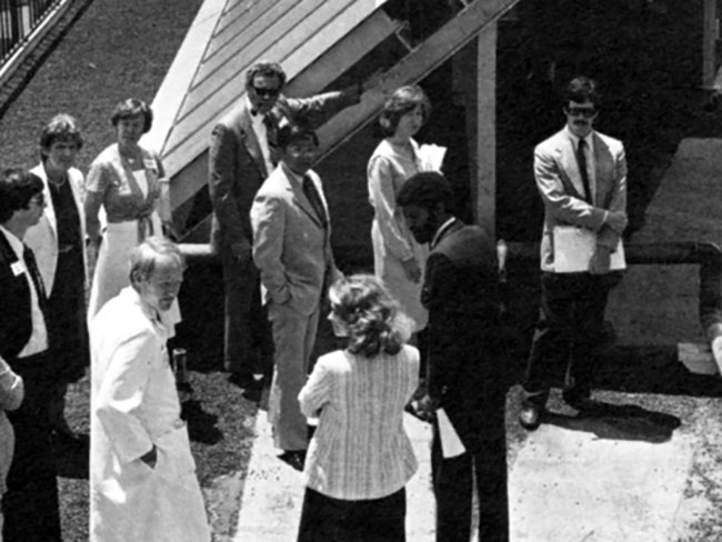 black and white photo from the 1980s with a group of staff next to a solar panel